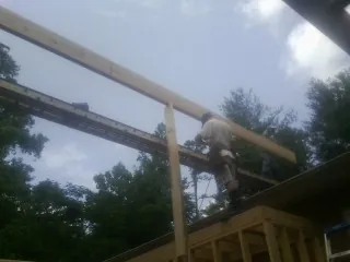 Carpenter setting a ridge beam over a new addition frame — Ice Dam Removal by Roofing Brothers in West Sayville