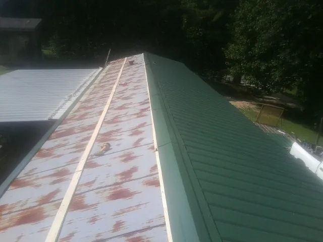 Old rusted panels beside newly installed green metal roofing — Wind Damage Roof Repair by Roofing Brothers in West Sayville