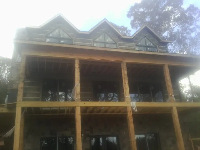 Dormers and porch framing on a large log home under construction — Roof Coating work by our crew in West Sayville