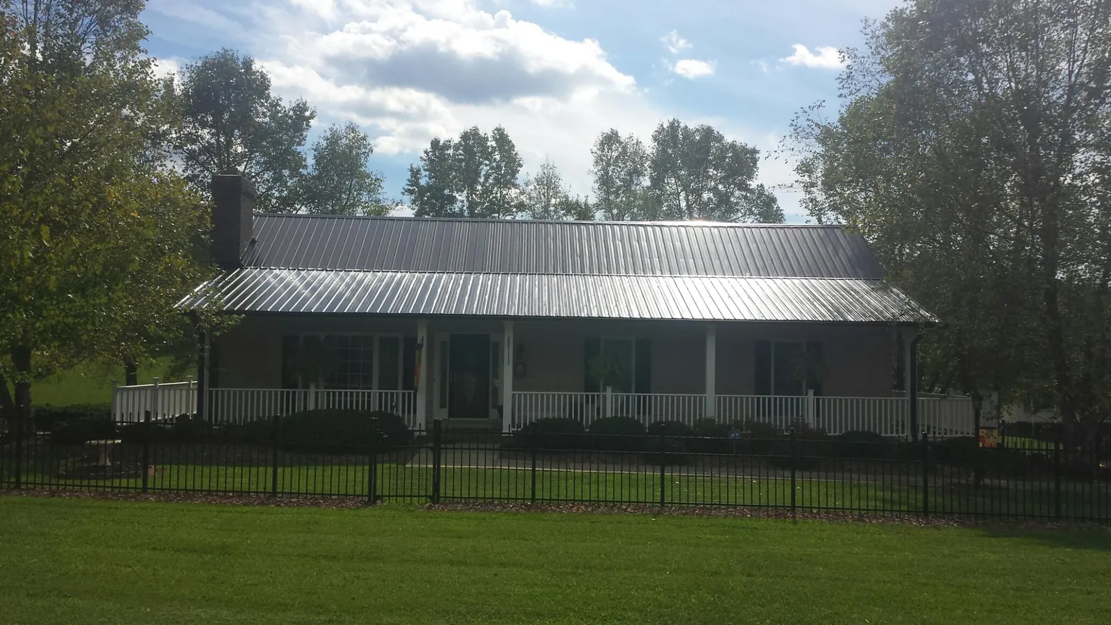 Gray metal roof on a brick ranch with a full width front porch — Gutter Guard Installation work by our crew in West Sayville