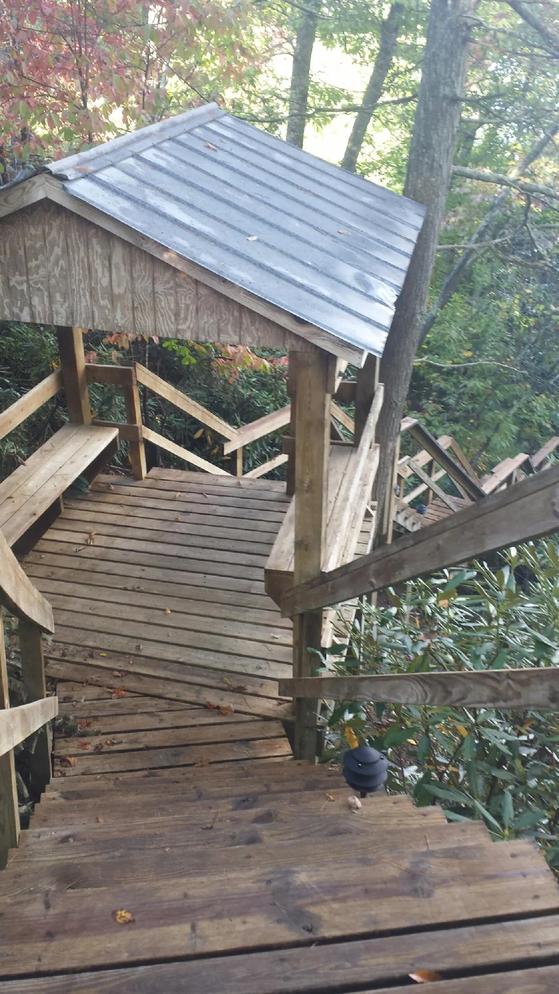 Metal roofed shelter over wooden steps on a wooded walkway — Skylight Repair & Installation work by our crew in West Sayville