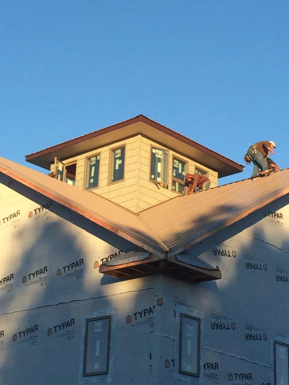 Roofers working around a rooftop cupola on a new metal roof at sunset — Roof Waterproofing in West Sayville by Roofing Brothers